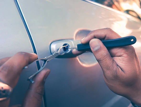 Technician unlocking a car door with tools, demonstrating secure lost key recovery service.