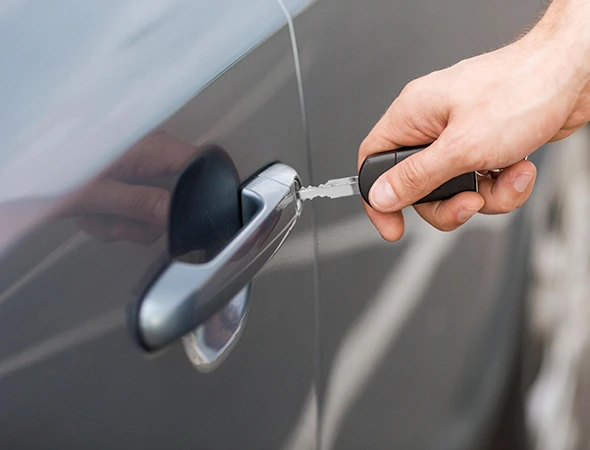 Person unlocking a car door using a duplicate key for vehicle access or locksmith service.