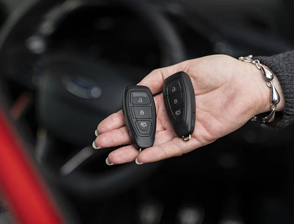 Woman holding car keys in hand, representing professional auto key replacement service.